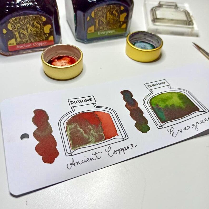 May include: Image of Diamine our ink bottle stamps can be matched to your favourite fountain pen ink brands. The image shows ink bottles, ink samples swatched onto ink swatch cards. The ink samples show the colour variations of the inks.