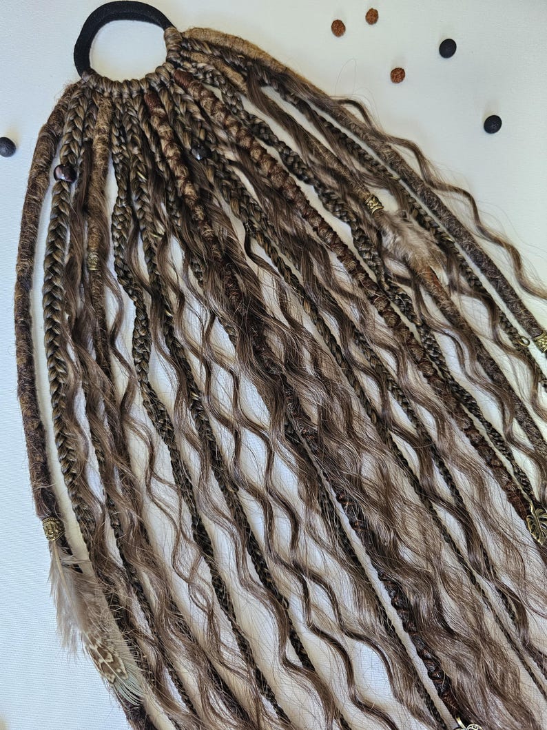 Hair on elastic band with auburn braids, curls, and dreadlocks, decorated with feathers, copper charms, beads, and threads. This handmade piece is perfect for bohemian hairstyles, adding texture and style effortlessly.