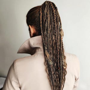 Braids on hairband with dreads on elastic band, combining curls, braids, and dreadlocks for a stylish look. This handmade temporary ponytail is adorned with feathers, copper charms, beads, threads, perfect for creating bohemian or festival hairstyles