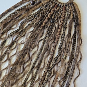 Handmade dreads on hairband featuring brown dreads, curls, and braids, perfect as dreadlock extensions. This unique brown dreads ponytail is decorated with feathers, copper charms, beads, and threads, ideal for creating bohemian-inspired hairstyles.