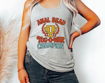 May include: Heather grey tank top with the text "ANAL BEAD Tug-O-War CHAMPION" in a retro font. The design includes a trophy graphic. The tank top is worn with blue jeans.