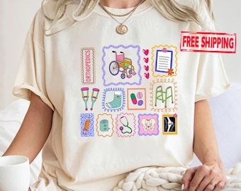 May include: A cream-colored t-shirt featuring a colorful graphic print of various medical and orthopedic icons, including a wheelchair, crutches, a cast, a walker, a stethoscope, a syringe, pills, a pelvis, and an X-ray, all arranged in frames.