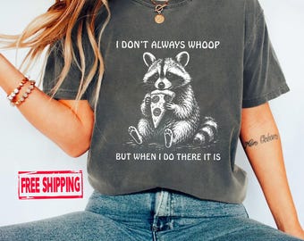 May include: A charcoal grey short-sleeved t-shirt featuring a white graphic of a raccoon eating a slice of pizza. The text above the raccoon reads I DON'T ALWAYS WHOOP and the text below reads BUT WHEN I DO THERE IT IS in a simple white font.