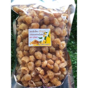May include: A transparent plastic bag filled with dried longan fruit. The fruit is a light brown colour and has a wrinkled texture. A small white and yellow label with text in a foreign language is attached to the bag.