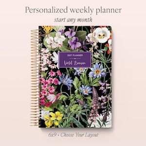 May include: A spiral-bound weekly planner with a black cover featuring a colourful botanical print of various flowers. A central purple rectangular label displays the text 2027 PLANNER and the name Violet Benson. The text Personalized weekly planner start any month and 6x9 Choose Your Layout is visible.