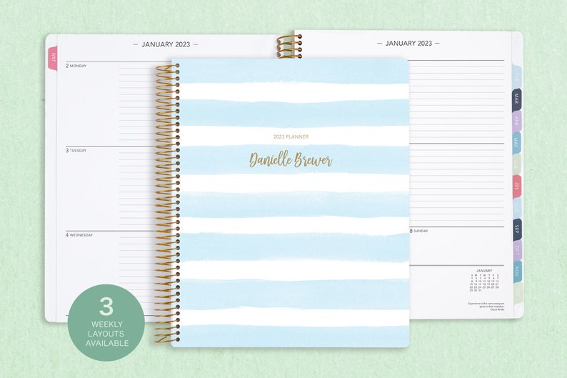 8.5x11" Posy Paper Co. 2023/2024 weekly planner with the blue watercolor stripes cover design showcasing horizontal layout in the background.