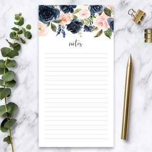 May include: A white notepad with a floral design at the top. The design features pink and blue flowers with green leaves. The notepad has a black line at the top that says "notes".