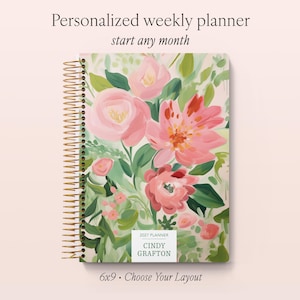 May include: A spiral-bound weekly planner with a floral cover featuring painted pink flowers and green foliage. The cover displays the text Personalized weekly planner, start any month, 2027 PLANNER, CINDY GRAFTON, and 6x9 • Choose Your Layout.
