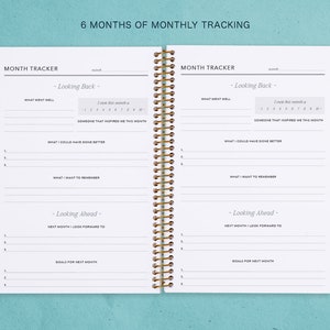 May include: A white planner with a gold spiral binding. The planner has a section for monthly tracking with headings for "Looking Back" and "Looking Ahead".