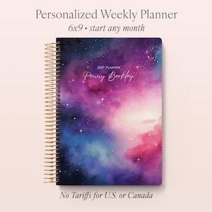 May include: A personalised weekly planner with a galaxy design. The cover features a vibrant mix of purple, pink, and blue hues, with a gold spiral binding. The planner measures approximately 15 x 23 cm and is labelled "2027 Planner" with the name "Penny Berkley".