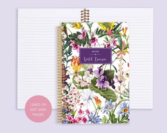 Puede incluir: Un cuaderno blanco de espiral con un diseño floral con flores moradas, rosas, amarillas y azules. La portada tiene el texto "NOTES Violet Benson". El cuaderno tiene páginas rayadas o de cuadrícula de puntos.