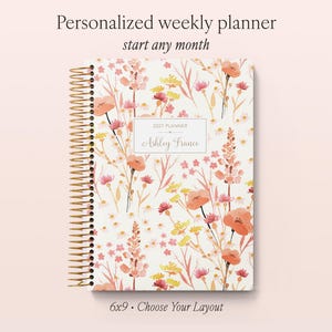 May include: A 6x9 personalised weekly planner with a white cover featuring a watercolour floral pattern in shades of orange, pink, and yellow. The cover includes a central rectangular label with the text 2027 PLANNER and ASHLEY FRANCE.