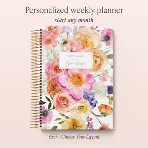 May include: A personalised weekly planner with a gold spiral binding, featuring a vibrant watercolour floral print in shades of pink, orange, yellow, and purple. The cover displays the text 2027 PLANNER and the name Grace Myer in a central box.