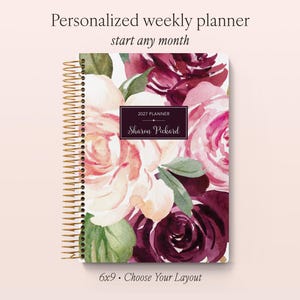 May include: A personalised weekly planner with a gold spiral binding, featuring a watercolour floral pattern in shades of burgundy, pink, and green. The cover displays the text 2027 PLANNER and Sharon Pickard in a central dark rectangular label.