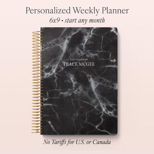 May include: A personalised weekly planner with a black marble design. The planner is 15 x 23 cm and has a gold spiral binding. The text "2027 PLANNER" and a name are printed on the cover. The planner is designed to start any month.