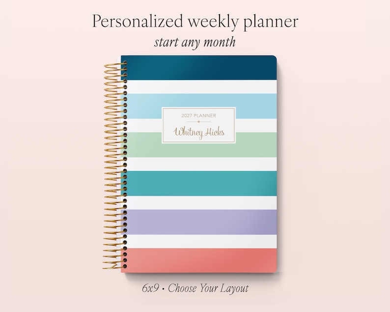 Puede incluir: Una agenda semanal personalizada con encuadernaci&oacute;n en espiral dorada, con rayas horizontales en azul oscuro, azul claro, blanco, verde, cerceta, lavanda y coral. Una etiqueta blanca central muestra el texto 2027 PLANNER y Whitney Hicks.
