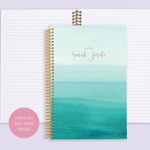 May include: A teal and blue watercolor design notebook with gold spiral binding. The cover says "Notes" and "Sarah Jerde". The notebook has lined or dot grid pages.