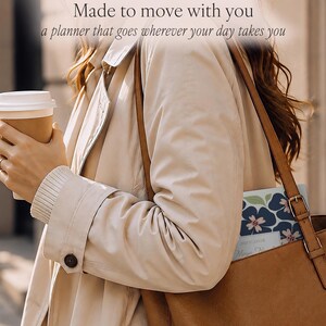 May include: A planner with a dark blue and pink floral pattern tucked into a brown leather tote bag. The text "Made to move with you" and "a planner that goes wherever your day takes you" is visible at the top of the image above the bag.