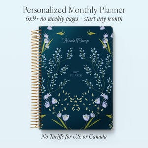 May include: A 6x9 inch personalized monthly planner with a dark blue cover featuring a symmetrical floral pattern in light blue and green. The cover displays the text Nicole Camp, 2027 PLANNER, Personalized Monthly Planner, and No Tariffs for U.S. or Canada.