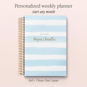 May include: A personalised weekly planner with a light blue and white horizontal striped cover, gold spiral binding, and the text 2027 PLANNER and Megan Chandler printed on the front. The planner measures 15.24x22.86 cm and includes the text start any month.