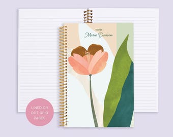 May include: A spiral bound notebook with a floral design on the cover. The cover features a pink and brown tulip with green leaves on a white background. The notebook has gold wire binding and the text "NOTES Marie Davison" is printed on the cover.