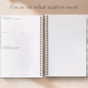 May include: Open planner with lined pages and gold spiral binding. The text "Focus on what matters most" is at the top. The planner includes sections for priorities and to-do lists, with tabbed dividers for organization.