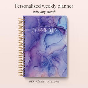 May include: A personalised weekly planner with a gold spiral binding, featuring an abstract purple and blue ink wash cover design. The text reads Personalised weekly planner, start any month, 2027 PLANNER, Elizabeth White, and 6x9 • Choose Your Layout.