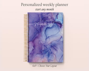 May include: A personalized weekly planner with a gold spiral binding, featuring an abstract purple and blue ink wash cover design. The text reads Personalized weekly planner, start any month, 2027 PLANNER, Elizabeth White, and 6x9 • Choose Your Layout.