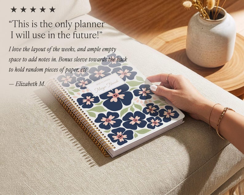 May include: A spiral-bound planner featuring a white cover with a repeating pattern of dark blue flowers with light pink centers and sage green leaves. A central white rectangular label displays the text 2025 PLANNER and Maya Novak.