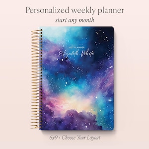 May include: A spiral-bound weekly planner with a galaxy-themed cover featuring shades of blue, purple, and pink. The cover displays the text 2027 PLANNER and the name Elizabeth White. The planner measures 15.24x22.86 cm and includes a gold-toned coil.