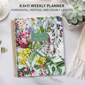 May include: An 8.5x11 weekly planner with a gold spiral binding and a floral pattern. The cover features a variety of flowers in shades of pink, purple, yellow, and blue on a light blue background. The planner is labelled "2024 Planner" and "Chelsea Grant".