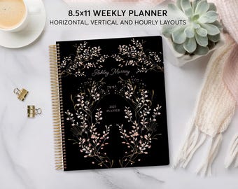 May include: A black 8.5x11 weekly planner with a gold spiral binding. The cover features a floral design with gold and pink accents. The text "Ashley Murray" and "2023 Planner" is printed on the cover.