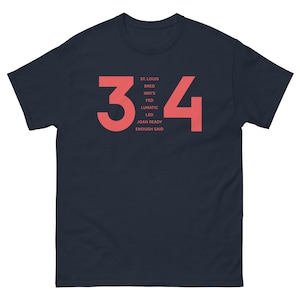 May include: A navy blue t-shirt with the numbers 34 printed in red. The text "ST. LOUIS BRED IMO'S FED LUNATIC LED JOAN READY ENOUGH SAID" is printed in red below the numbers.