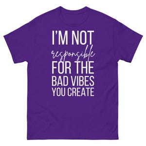 Puede incluir: Una camiseta morada con el texto blanco "I'M NOT responsible FOR THE BAD VIBES YOU CREATE". La camiseta tiene mangas cortas y cuello redondo. El texto está en negrita, sin serifa, con "responsible" en cursiva.