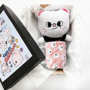 K&ouml;nnte beinhalten: Eine schwarze Box mit einem blauen und wei&szlig;en Design, das eine Comic-Katze und den Text "This is Comprox" und "Annyeong!" zeigt. Die Box ist ge&ouml;ffnet und im Inneren befindet sich ein wei&szlig;es Pl&uuml;schkatzenspielzeug mit einem schwarzen Shirt und eine wei&szlig;e Tasse mit einem rosa-wei&szlig;en Comic-Katzenmuster.