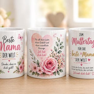 Könnte beinhalten: Drei weiße Keramikbecher mit Blumendesigns und deutschem Text. Die Becher zeigen rosa Blumen, Schmetterlinge und Sätze wie "Beste Mama der Welt" und "Alles Gute zum Muttertag". Jeder Becher hat einen weißen Henkel.