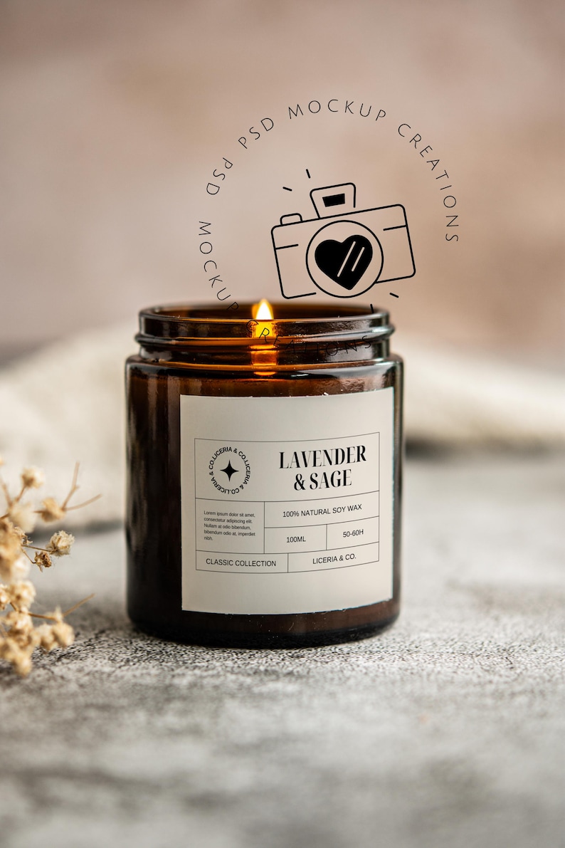 May include: A lit brown glass jar candle with a white label that reads "Lavender & Sage." The candle is part of the "Classic Collection" and made with 100% natural soy wax. The candle has a burn time of 50-60 hours.