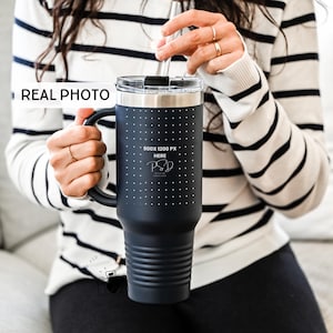 May include: A black stainless steel travel mug with a handle and a black lid. The mug has a white polka dot pattern and the text "900x1200 PX HERE" is printed on the side.