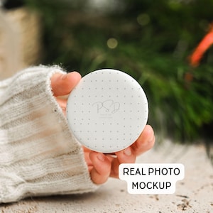 May include: A white, round product mockup with a dotted pattern and the text "PSD CREATIONS" in a script font. The words "REAL PHOTO MOCKUP" are in a white rectangle. The product is held in a hand.