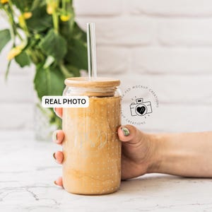 May include: A clear glass tumbler with a bamboo lid and a glass straw, filled with a light brown beverage. The tumbler has a dotted pattern and engraved initials. The words "REAL PHOTO" are visible on the image.