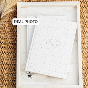 May include: Three white notebooks with a small gray polka dot pattern. The top notebook has the text "PSD Mockup Creations" in gray. The bottom notebook has the text "PSD Mockup Creations" in black.