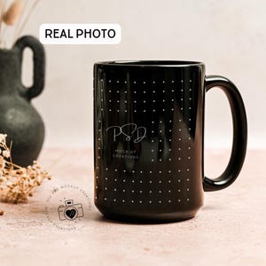 May include: A black ceramic mug with a large handle, adorned with small white polka dots. The mug features the text "PSD MOCK UP CREATIONS" in a script font. The words "REAL PHOTO" are in the top left corner.
