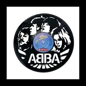 Op de afbeelding: Zwarte vinylplaat met een wit silhouet van de band ABBA. Het middenlabel van de plaat is blauw en toont de naam van de band en de titel van het nummer. De naam van de band, ABBA, staat ook in het wit onderaan de plaat.