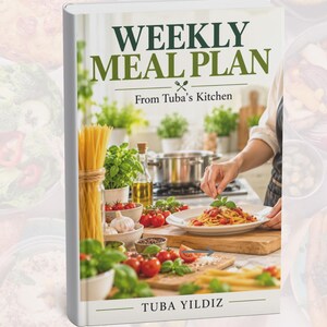 May include: A hardcover book titled Weekly Meal Plan From Tuba's Kitchen by Tuba Yildiz. The cover features a photograph of a kitchen scene with pasta, fresh tomatoes, basil, garlic, and a person plating a meal on a wooden cutting board.