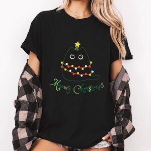 May include: Black t-shirt with a graphic of a black cat dressed as a Christmas tree with a star on top. The text "Meowy Christmas" is printed below the cat.
