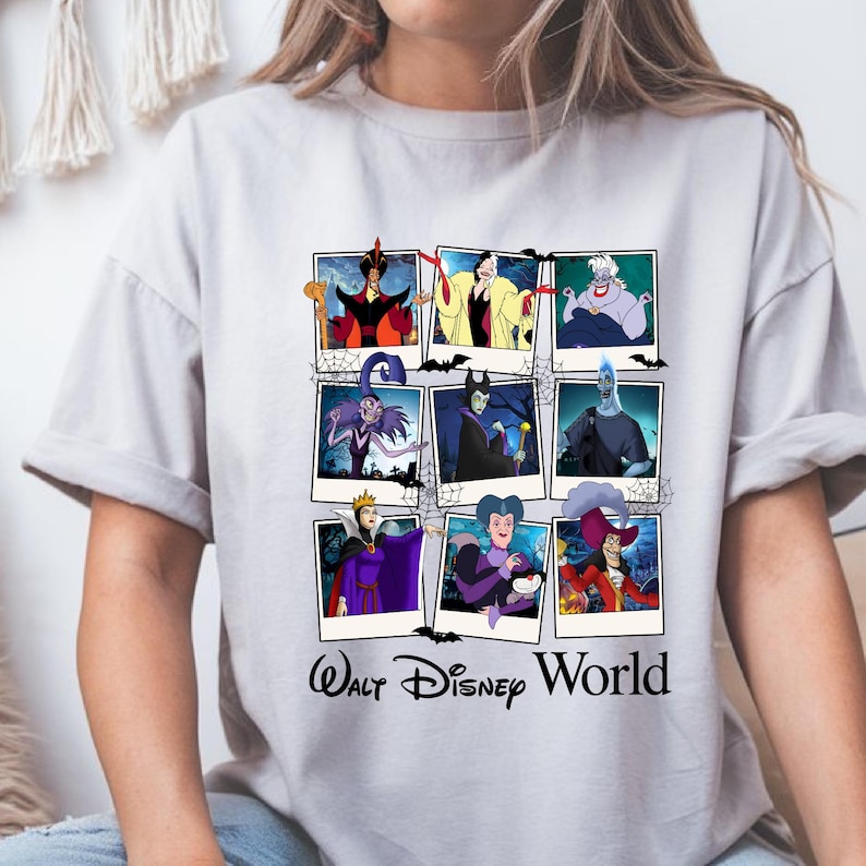 K&ouml;nnte beinhalten: Ein hellgraues T-Shirt mit einer Collage von Disney-B&ouml;sewichten in Polaroid-Rahmen. Die Bilder zeigen Charaktere wie Dschafar, Cruella de Vil und Ursula. Darunter steht "Walt Disney World".