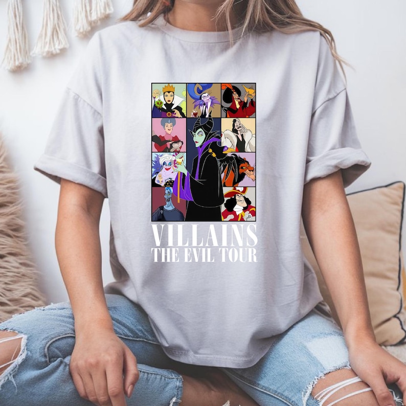 May include: A gray t-shirt with a graphic of Disney villains. The graphic features Maleficent, Ursula, Cruella de Vil, and other villains. The text "VILLAINS THE EVIL TOUR" is printed below the graphic.