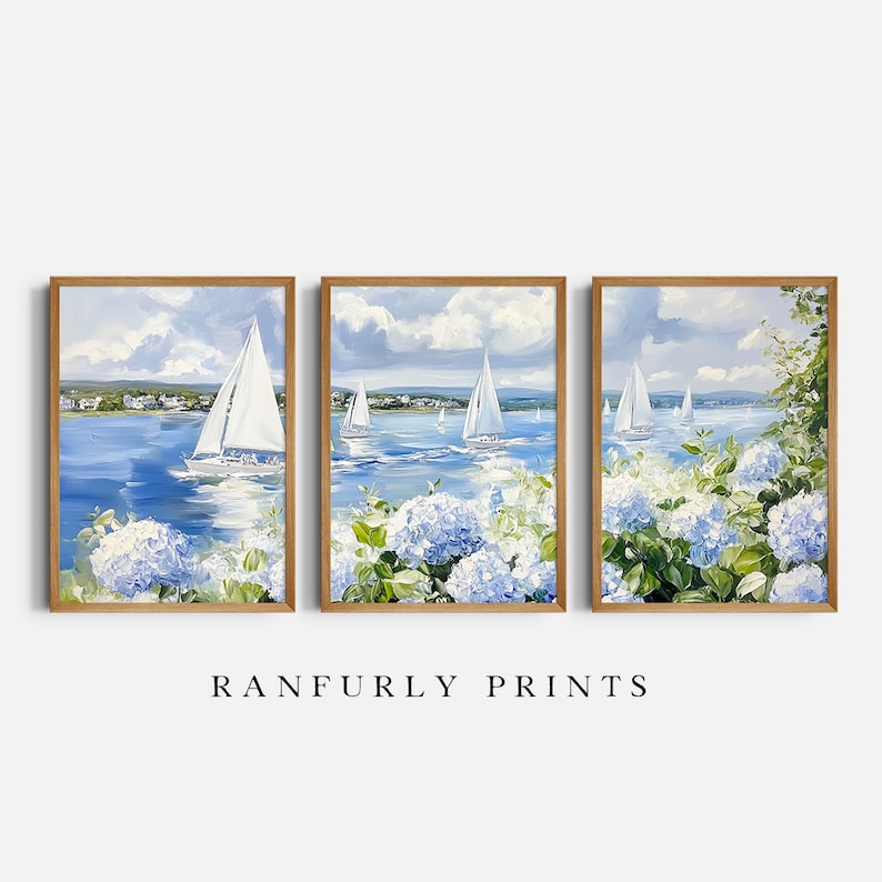 May include: Set of three framed art prints featuring sailboats on a blue sea, white clouds, and blue hydrangea flowers. The artwork has a wooden frame. The text "RANFURLY PRINTS" is at the bottom.