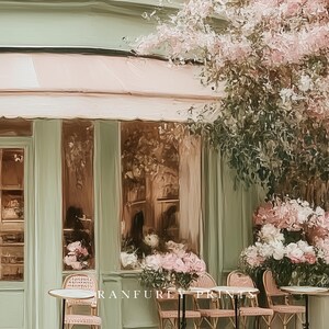 K&ouml;nnte beinhalten: Eine k&uuml;nstlerische Darstellung eines Caf&eacute;-Au&szlig;enbereichs mit hellgr&uuml;ner Fassade und rosa Markise. Korbst&uuml;hle und kleine Tische sind drau&szlig;en aufgestellt. Die Szene ist mit rosa und wei&szlig;en Blumen geschm&uuml;ckt und schafft eine charmante, einladende Atmosph&auml;re.