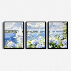 May include: Set of three framed art prints depicting sailboats on a blue sea under a cloudy sky. The artwork features white sailboats, blue water, and white and blue hydrangea flowers in the foreground. The frames are black.